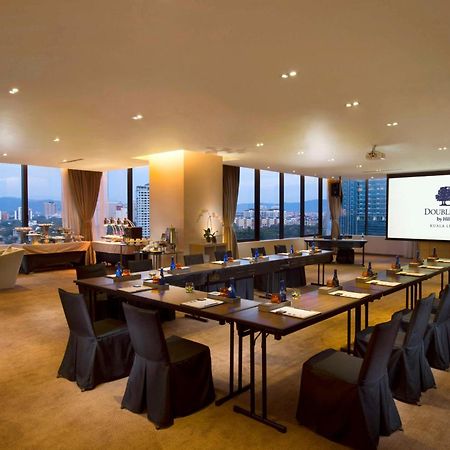 Doubletree By Hilton Kuala Lumpur Ξενοδοχείο Εξωτερικό φωτογραφία The photo shows a modern conference room. It features a long table arranged for a meeting, with black chairs and notepads placed at each seat. The room has large windows that let in natural light and offer a view of the city outside. On one wall, the