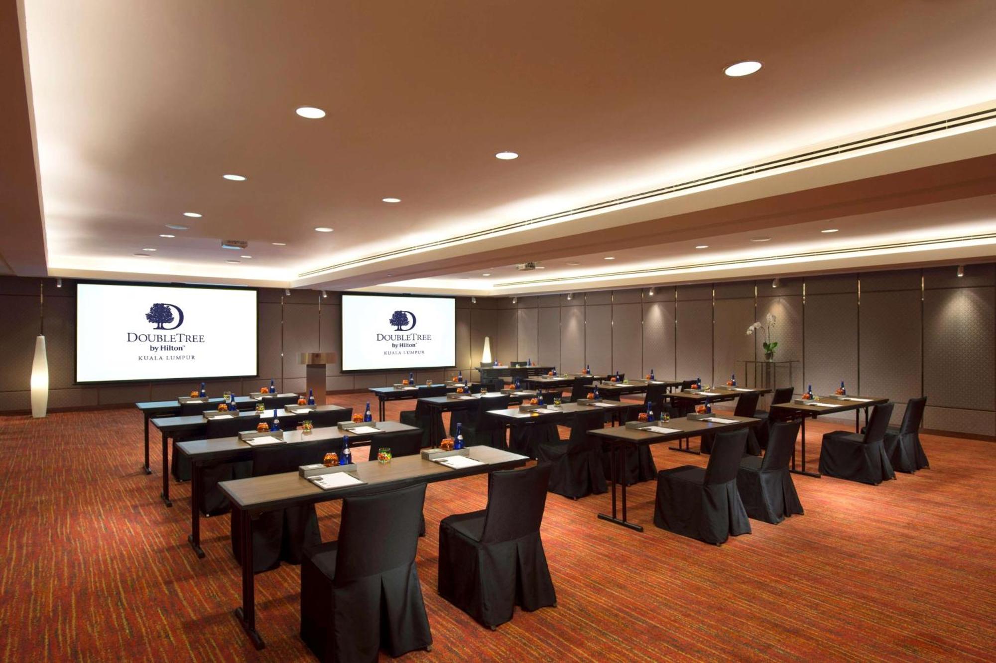 Doubletree By Hilton Kuala Lumpur Ξενοδοχείο Εξωτερικό φωτογραφία The image shows a conference or meeting room setup. There are several rows of tables arranged for participants, each covered with a black tablecloth. The tables are equipped with stationery, suggesting that the space is intended for a professional ga